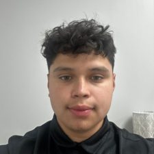 Elwuin Villalta, PTA A young man with short, curly dark hair wearing a black collared shirt is facing the camera against a plain light-colored background.